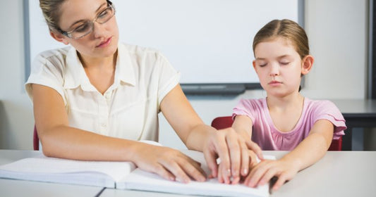 Child learning to read in Braille with a teacher