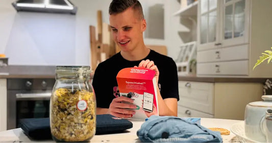 Person in black t-shirt opening the Hable Speechlabel starter pack. In front of him are different items with labels on it.