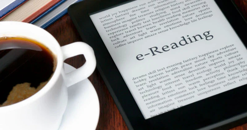 A cup of black coffee on a white saucer next to an e-reader displaying text about e-Reading, placed on a wooden surface.
