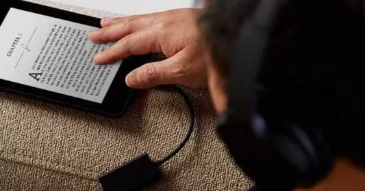  A person wearing headphones holds an e-reader displaying a page from Chapter 1 of a book.