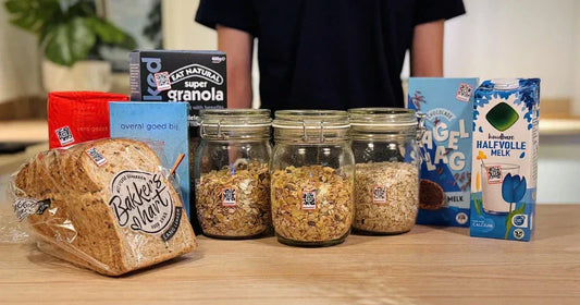 Breakfast items on a table—bread, jars of oats and granola, and milk—each labeled with small Speechlabel QR stickers for audio identification.