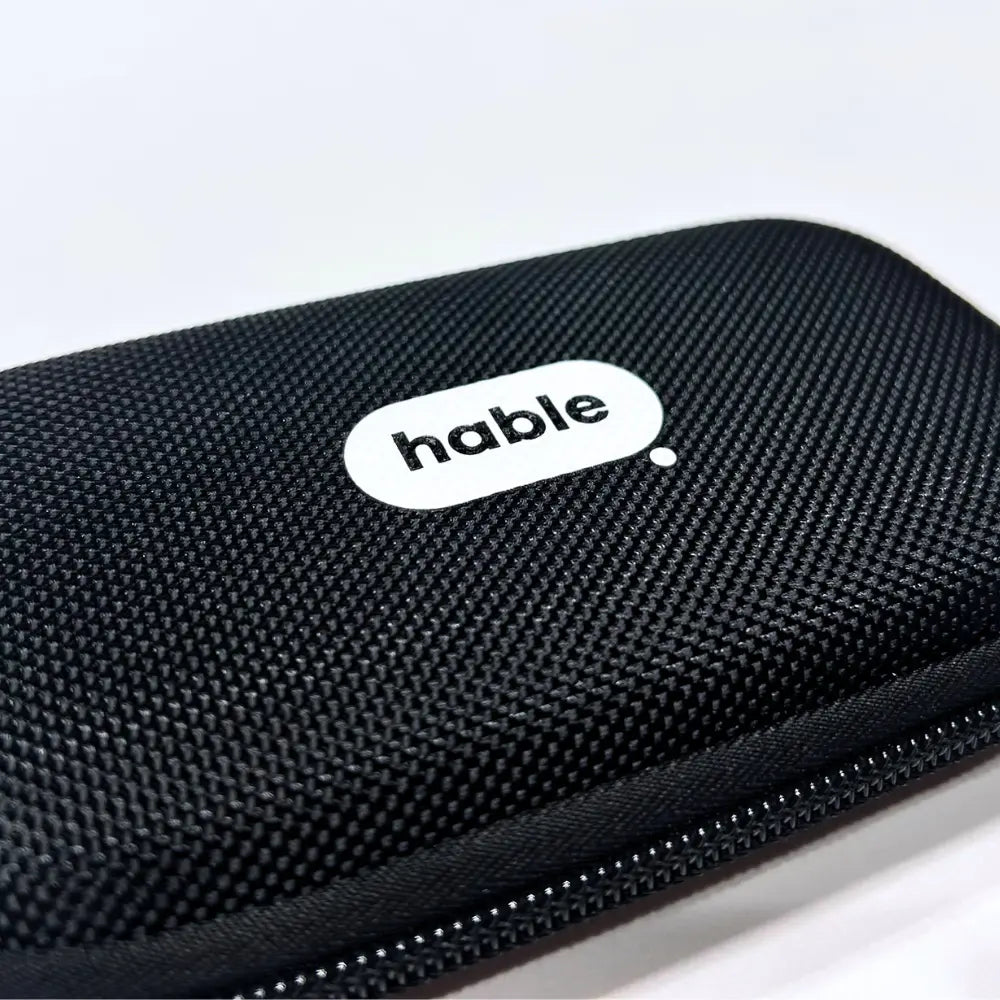 Close-up of the black hard-shell carry case showing its textured woven surface, zipper edge, and white oval badge with the black "hable" logo.