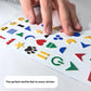 A close-up, angled photograph of a hand moving across a sheet of raised, colorful tactile stickers. The focus is on the 3D texture of the icons, such as a green power symbol and a black paw print. A text overlay at the bottom reads, "The perfect tactile feel to every sticker."