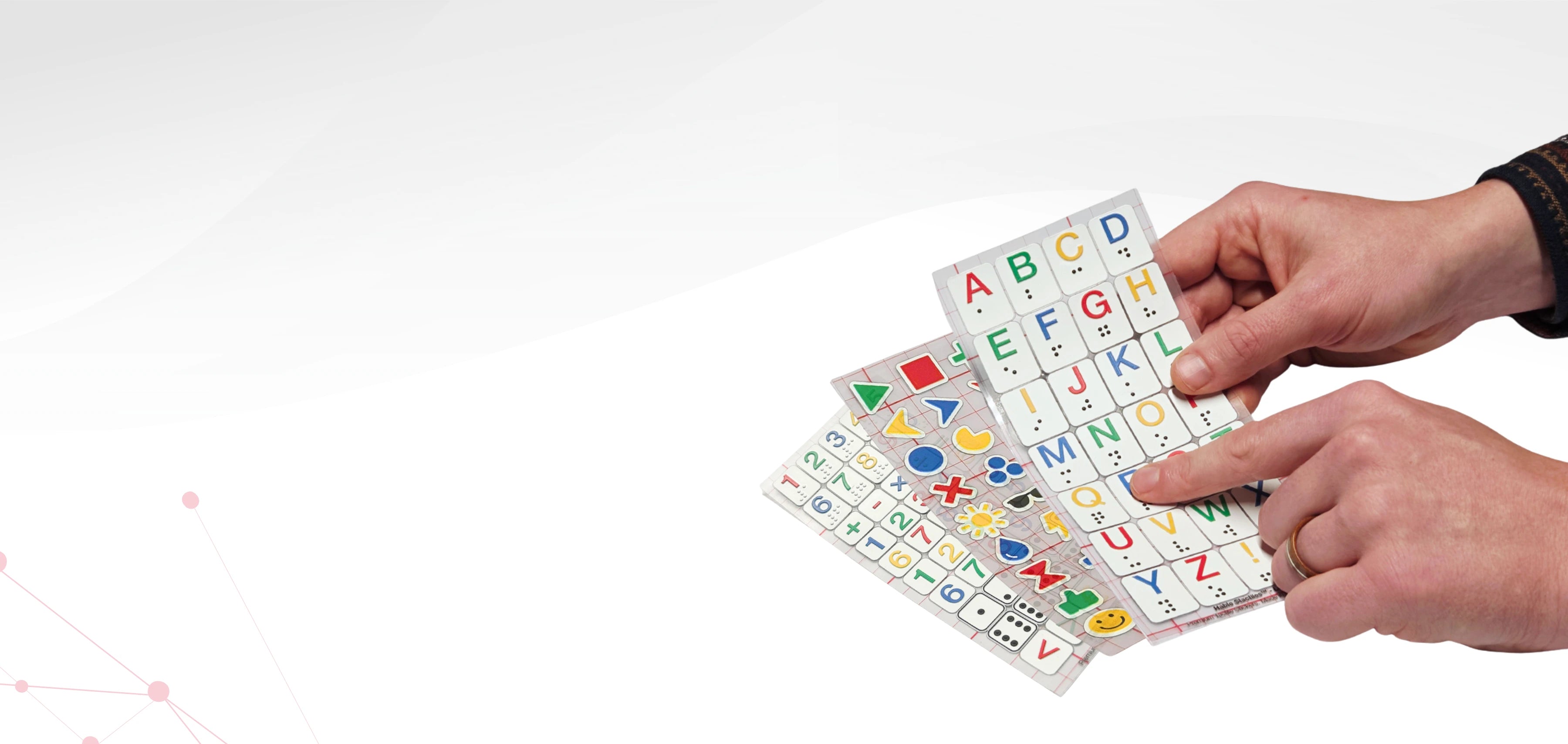 Hands holding a colorful alphabet card with letters and symbols on a white background. Showing different type of Stactile Stickers.