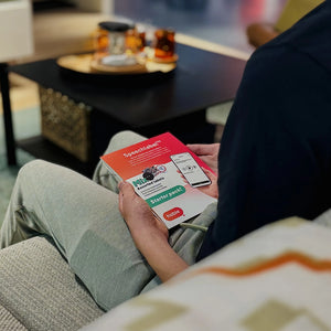 Image from the back of a person opening the Speechlabel starter pack. Person is sitting on a couch in the living room.