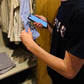 Person using a smartphone with the Speechlabel app opened. About to tap the speechabel button on a blue shirt in his wardrobe.