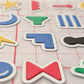 A close-up view of Stactiles icons showing raised, colorful symbols with crisp edges on a transparent grid backing, highlighting their textured, tactile surface.